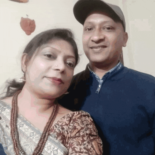 a man and woman are posing for a picture and the man is wearing a baseball cap