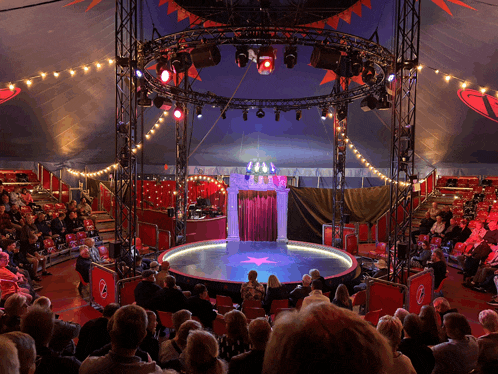 a crowd of people watching a circus show with a red star in the middle