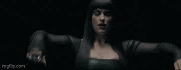 a woman in a black dress is dancing in the dark in a video .