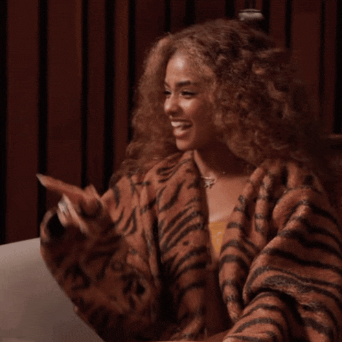 a woman with curly hair wearing a tiger print coat