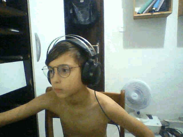 a shirtless boy wearing headphones and glasses