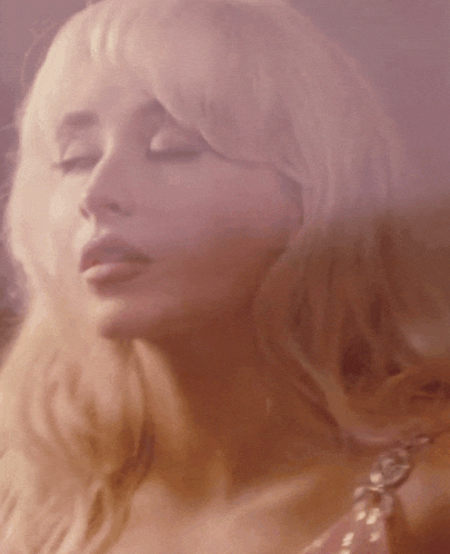 a close up of a blonde woman 's face with her eyes closed .