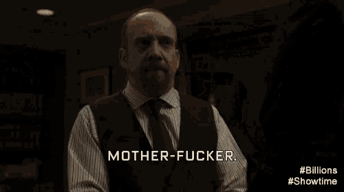a man in a suit and tie is standing in a dark room with a woman standing behind him .