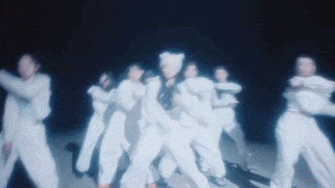 a group of people in white jumpsuits are dancing in the dark .