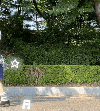 a person standing in front of a hedge with a white star and the letter a on the ground