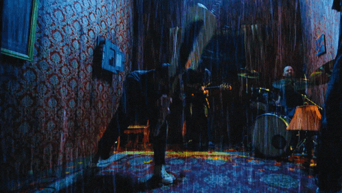 a person playing a guitar in the rain with a drum and a lamp in the background