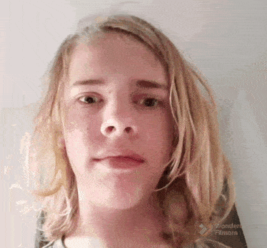 a young boy with long blonde hair is making a face with wondershare filmora