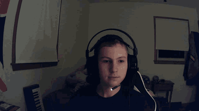 a boy wearing headphones and a microphone looks at the camera