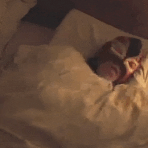 a person in a wrestling mask is sleeping in a bed