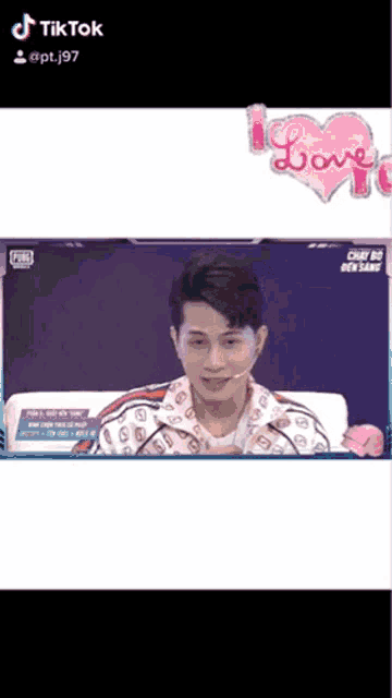 a man is sitting in front of a screen with a pink heart and the word love on it