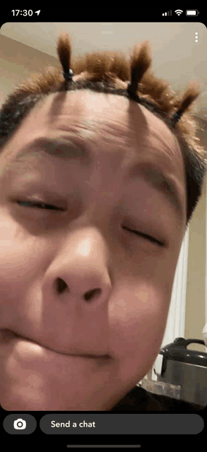 a phone screen shows a person making a funny face and says send a chat at the bottom