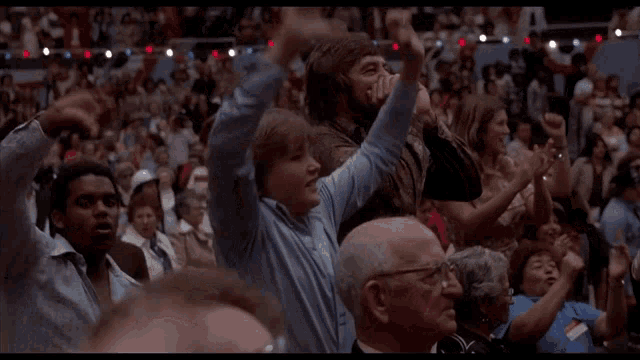 a crowd of people are clapping their hands in the air