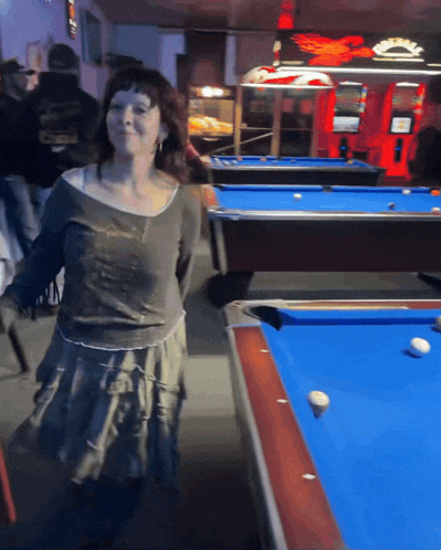 a woman stands in front of a pool table with a harley davidson logo on the wall