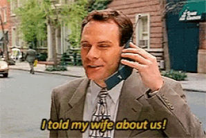 a man in a suit and tie is talking on a cell phone while saying i told my wife about us