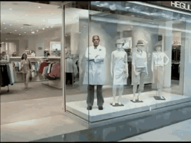 a man in a lab coat stands in front of a display of mannequins in a store called hegul