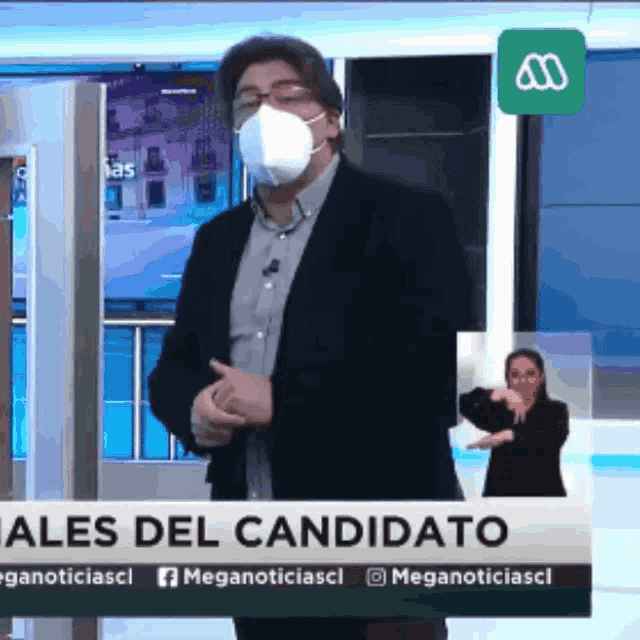 a man wearing a face mask is standing in front of a sign that says ales del candidato