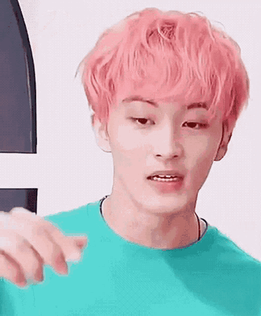 a young man with pink hair is wearing a green t-shirt .