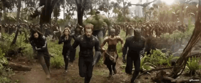 a group of people are running through a forest in a movie scene .