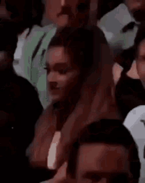 a woman is sitting in a crowd of people and looking at something .