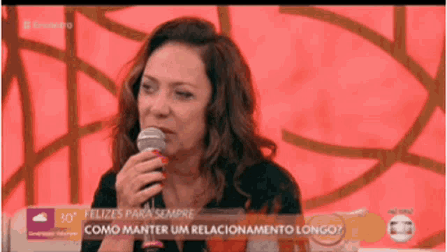 a woman is crying while holding a microphone in front of a sign that says felizes para sempre