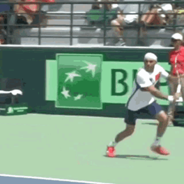 a man is playing tennis on a court with a bnp sign behind him