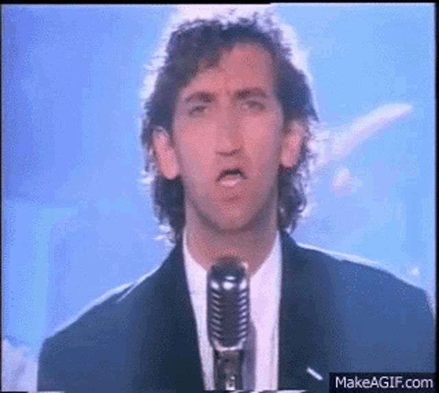 a man in a suit and tie is singing into a microphone on a stage .