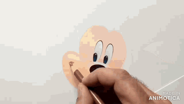 a person is drawing mickey mouse 's face with a pencil .
