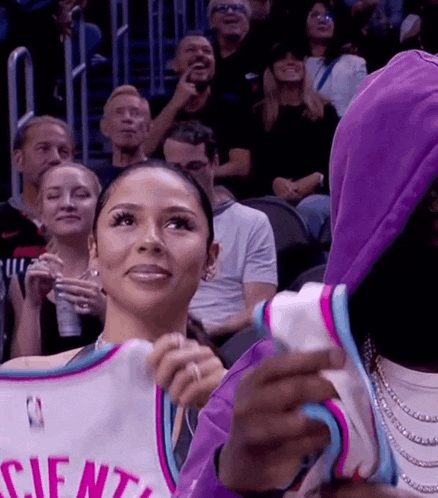 a woman is holding a basketball jersey while sitting in the stands .