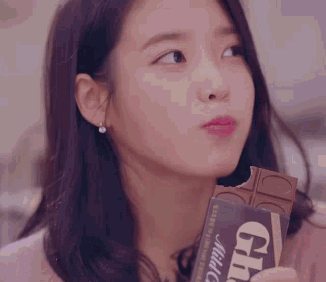 a close up of a woman eating a chocolate bar