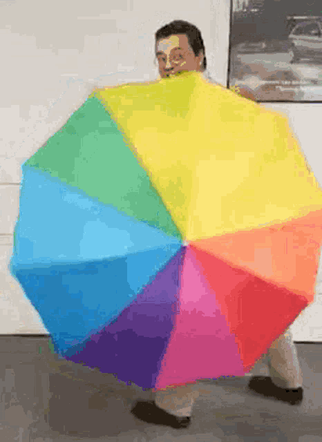 a man is holding a rainbow colored umbrella in front of him