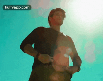 a man in a black shirt is standing in front of a blue sky with the words kulfyapp.com above him