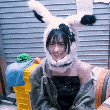 a woman wearing a bunny hat and a jacket is smiling