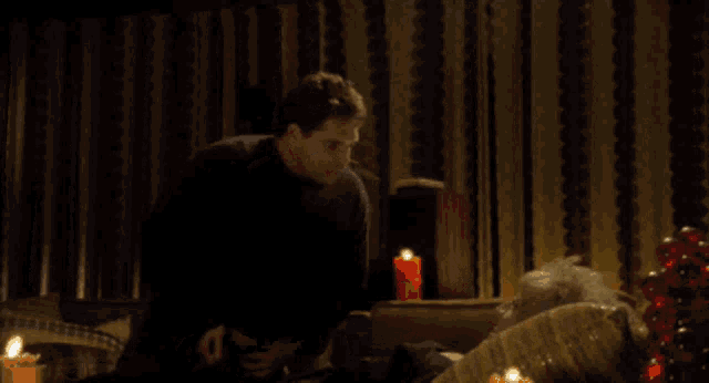 a man is talking to an elderly woman who is laying on a couch with candles and says do you got any porn