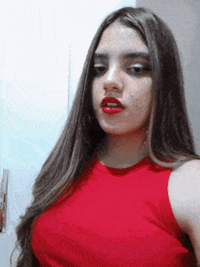 a woman with long hair and red lipstick is wearing a red top