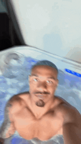 a shirtless man is taking a selfie in a jacuzzi