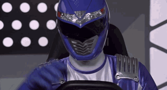 a blue power ranger is sitting in a car with a steering wheel