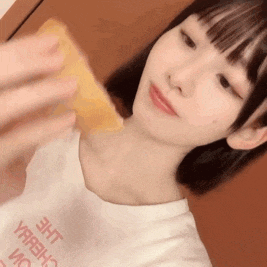 a woman wearing a white t-shirt that says the yareh on it is holding a piece of food .