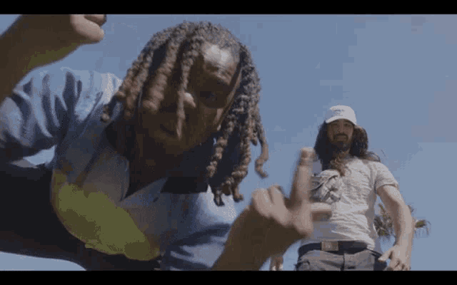 a man with dreadlocks giving the middle finger to the camera