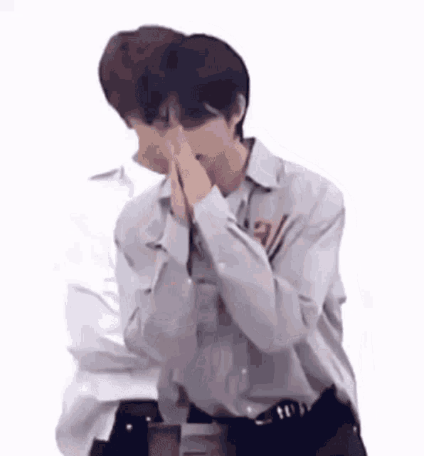 a man is covering his face with his hands .