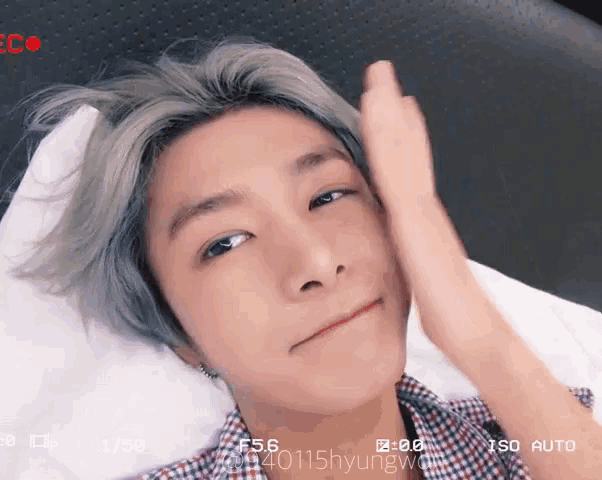 a young man laying on a bed with his hand on his forehead and a recording of him being taken