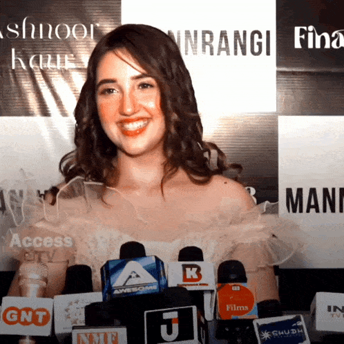 a woman stands in front of several microphones with one that says awesome
