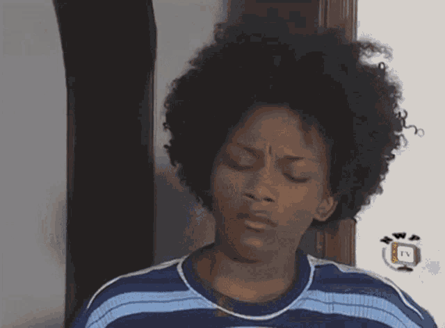 a woman with curly hair is wearing a blue and white striped shirt .
