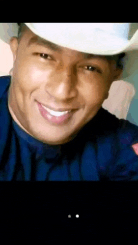 a man wearing a cowboy hat and a blue shirt smiles for the camera