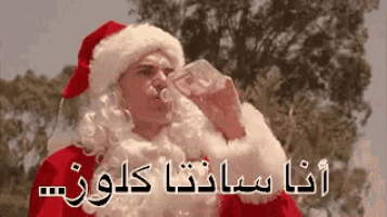 a man dressed as santa claus is drinking from a glass .