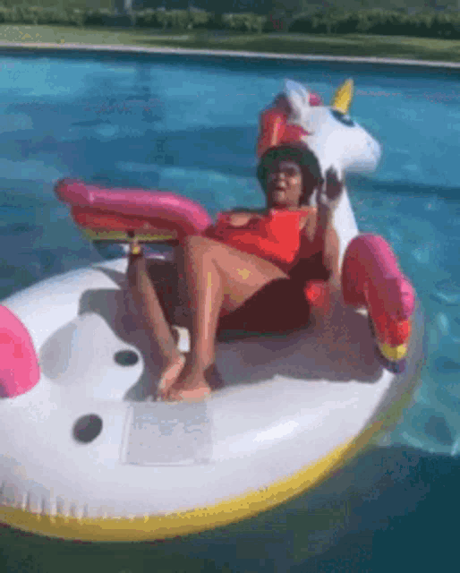 a woman is sitting on a unicorn float in a swimming pool .