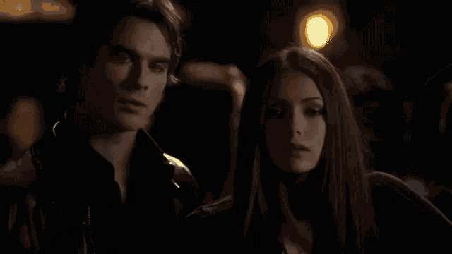 a man and a woman are standing next to each other in a dark room .