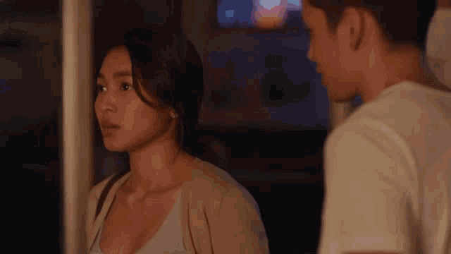 a man and a woman are looking at each other in a room