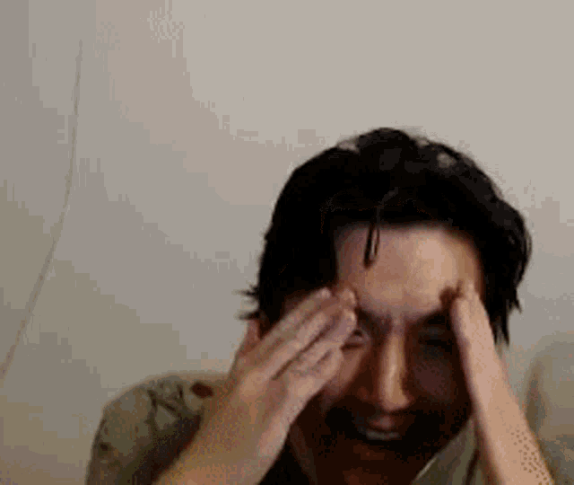 a man is covering his face with his hands and smiling .