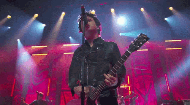 a man singing into a microphone while playing a guitar on a stage .
