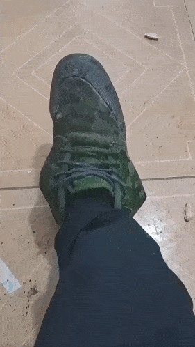 a person 's foot wearing a pair of green camouflage shoes